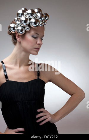 Ritratto di una giovane donna, palle di Natale come ornamenti per capelli, top in nero Foto Stock