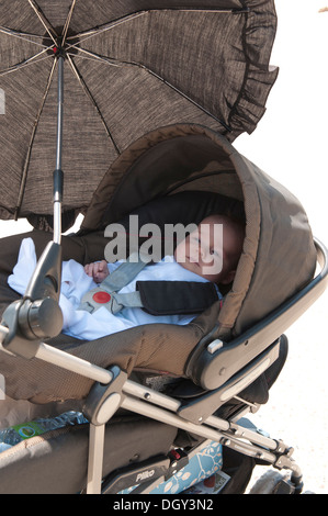 Little Baby girl strapped nel suo passeggino Foto Stock