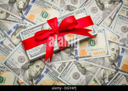 Pila di recente progettato U.S. Banconote da cento dollari Regalo ad arco rosso. Foto Stock