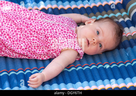 Little baby ragazza distesa verso il basso guardando la telecamera preoccupato Foto Stock