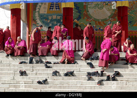 Monaci Tibetani che indossa vesti della Gelug o Gelug-pa fine seduta accanto a loro stivali rimosso nella parte anteriore del gruppo Hall Foto Stock