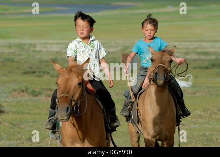 Due piccole 6-year-old boys mongola rottura nel brioso cavalli mongolo nei prati secchi, Lun Toev Aimak, Mongolia, Asia Foto Stock