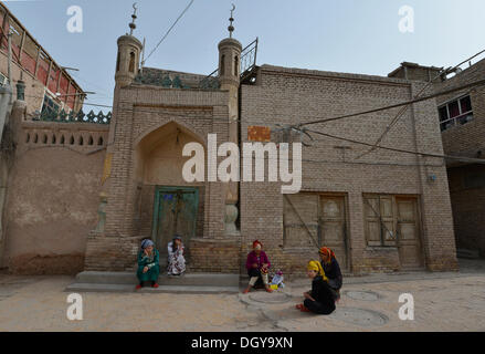 Le donne musulmane, Uiguri con colorate il velo seduti davanti ad una moschea, fango-case in mattoni, Uighur centro storico di Foto Stock