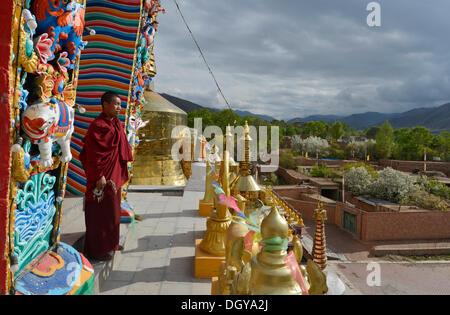 Il Tibetano monaco buddista su un nuovo dipinto e dorato, chorten stupa al Wutun Si Monastero, Tongren, Repkong, Qinghai Foto Stock