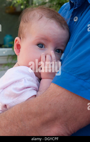 Close-up verticale di una piccola bambina che si terrà succhiare il suo pollice Foto Stock