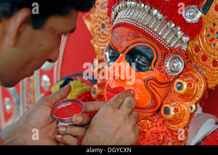 Dipingere il volto di un attore Theyyam, preparando per un rituale, vicino Kasargod, Nord Kerala, India del Sud, Asia Foto Stock