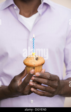 Uomo con muffin con candela singola sulla parte superiore Foto Stock