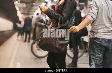 Giovane donna tramite telefono mobile di essere derubati da un pickpocket presso la stazione della metropolitana. Borseggio presso la stazione della metropolitana Foto Stock