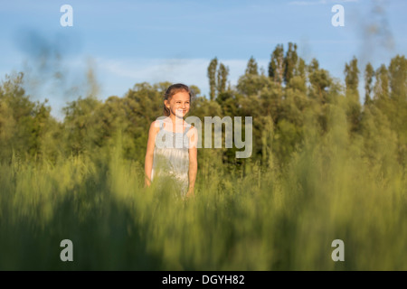 Una giovane ragazza vivace in piedi in un campo guardando la vista Foto Stock