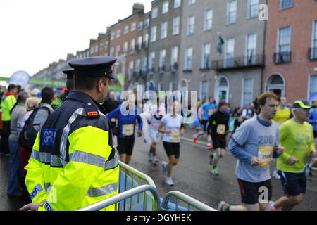 Dublino, Irlanda. Il 28 ottobre 2013. Due ufficiali di Garda (polizia irlandese) guarda le guide di passaggio. 14.500 corridori iniziato nella XXXIV incarnazione della Maratona di Dublino, nonostante le previsioni di forte vento e pioggia. La maratona ha visto un nuovo record di presenze con oltre 10,00 irlandese e 4.000 corridori stranieri. Credito: Michael Debets/Alamy Live News Foto Stock