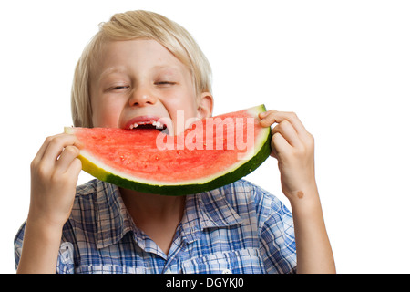 Un giovane ragazzo prendendo grosso morso di succose fette di cocomero. Isolato su bianco. Foto Stock