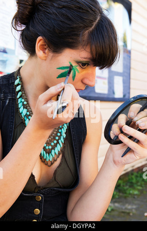 Una giovane donna dipinge il suo viso come parte del carnevale sfilano in Nimbin, protestando l' illegittimità della marijuana. Foto Stock