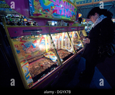 Giocare le macchine di scanalatura in un porticato sul molo di Brighton Foto Stock