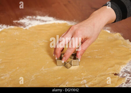 Donna di mano usando una formina per tagliare biscotti di Natale fuori della pasta Foto Stock
