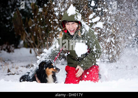 Giovane donna giocando con un pastore australiano cane nella neve, Austria Foto Stock