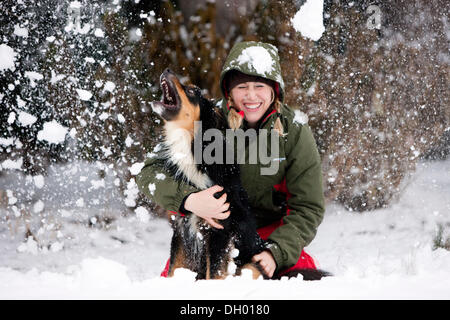 Giovane donna giocando con un pastore australiano cane nella neve, Austria Foto Stock