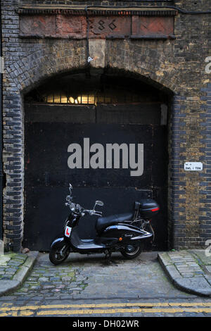 Entrata di un vecchio magazzino in fiore Street con uno scooter a motore parcheggiato di fronte, City of London, Londra, regione di Londra Foto Stock