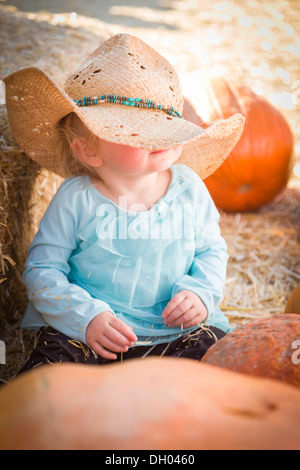Adorabile bambina con il cappello da cowboy in un paese ambiente rustico presso la Zucca Patch. Foto Stock