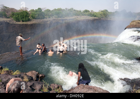 Devils Pool Victoria Falls; lato Zambia, persone in una vacanza di avventura nuoto sul bordo delle cascate in Devil's Pool, Zambia Africa Foto Stock
