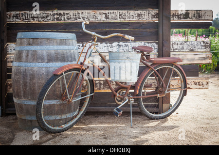 Vecchio arrugginito bicicletta antichi e botte di vino in un ambiente rustico ambiente all'aperto. Foto Stock