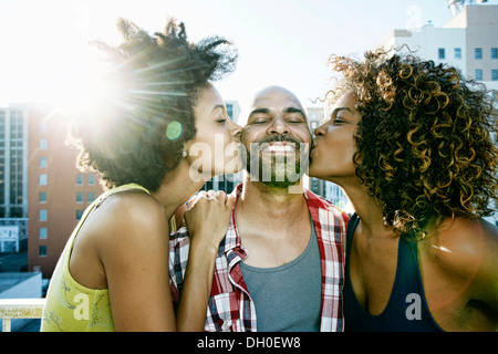 Le donne baciare uomo guance di urbano sul tetto Foto Stock