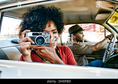 Donna che utilizza fotocamera vintage in auto Foto Stock