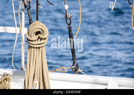 Funi dettagli su una vecchia nave a vela appeso di fronte blu acqua Foto Stock