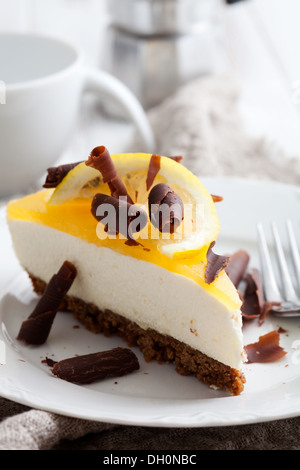 Cheesecake al limone con fettina di limone e riccioli di cioccolato Foto Stock