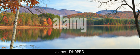 La mattina presto sole autunnale ha colpito gli alberi sulla riva lontana di Cooper lago in mezzo per vicino a Woodstock, NY Foto Stock