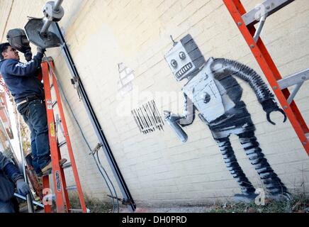 New York, NY, STATI UNITI D'AMERICA. 28 ott 2013. Banksy sulla posizione per Graffiti artist Banksy Robot di etichette con codice a barre e piccione in Coney Island, Stillwell e Nettuno Avenue, New York, NY Ottobre 28, 2013. Credito: Derek Storm/Everett raccolta/Alamy Live News Foto Stock