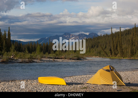 Camp sulla ghiaia bar, tenda e canoa, Pelly montagne dietro, superiore Liard River, Yukon Territory, Yukon Territory, Canada Foto Stock