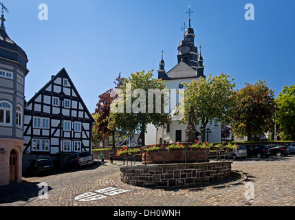 San Pietro Fontana con stemma comunale e la chiesa di San Heribert in Hallenberg, quartiere Hochsauerlandkreis Foto Stock