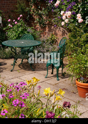 Attraente soleggiato giardino pavimentato patio con metallo verde tavolo e sedie, Barnsdale Gardens, Oakham, Rutland, Inghilterra, Regno Unito. Foto Stock