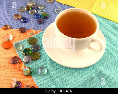 Outdoor tazza di tè in una tazza bianca con pietre su un sottofondo di materiale Foto Stock