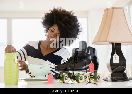 Razza mista donna mettendo tag prezzo su oggetti Foto Stock