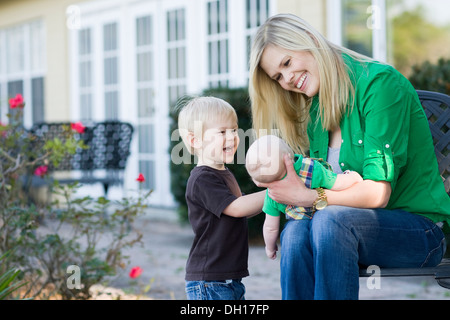 Madre caucasica rilassante con i bambini in giardino Foto Stock