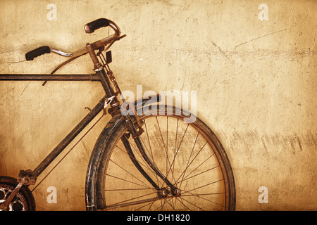 Vecchio arrugginito bicicletta vicino alla parete grunge Foto Stock