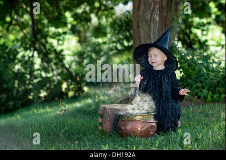 Poco halloween strega ebollizione , una pozione, all'aperto nel bosco Foto Stock