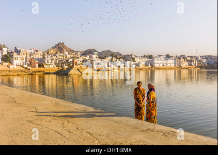 Pellegrini indù preparare a prendere un bagno rituale nel lago santo a Pushkar come Aurora rompe su questa piccola città. Foto Stock