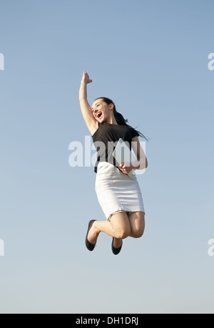 Gioioso salto con computer tablet Foto Stock