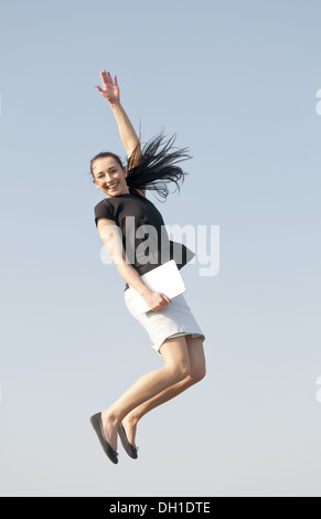 Gioioso salto con computer tablet Foto Stock