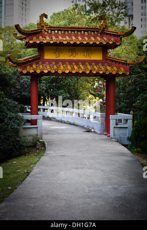 Cinese tradizionale set di gate in un lussureggiante parco verde all'interno di una città cinese Foto Stock