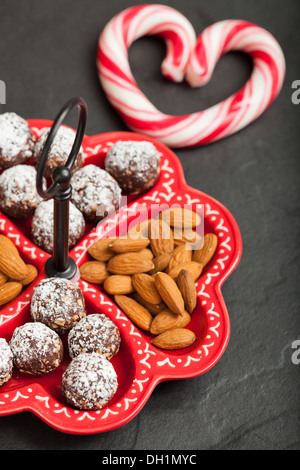 Primo piano del vassoio di mandorle e cioccolato di sfere e duri di cuore a portata di mano con red volute Foto Stock