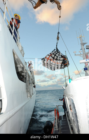 L'equipaggio a bordo del guardacoste vigili utilizza una gru per trasferire il contrabbando di una stazione della Guardia Costiera Miami smallboat equipaggio, 11 ott. 2013. Il carico totale trasferito è stato 15 balle di cocaina e 50 balle di marijuana con una stima di commercio all'ingrosso valu Foto Stock