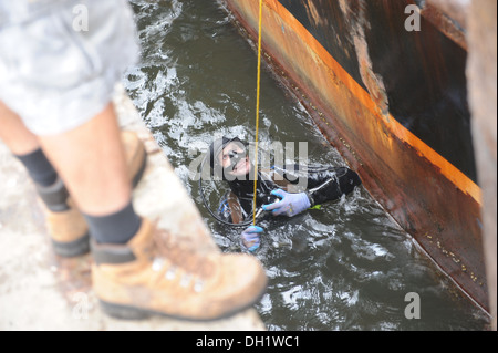 Un subacqueo, il tentativo di determinare la causa delle inondazioni, i colloqui per l'equipaggio della 88-piede gamberetti barca Sea King, ormeggiata al porto sicuro Marina in Atlantic Beach, Florida, Martedì, Ottobre 15, 2013. Il re del mare cominciò a prendere su acqua con quattro persone a bordo di 2 miglio Foto Stock