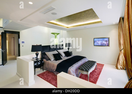 Oro incassato, illumina il soffitto sopra il letto con il nero di gettare e cuscini in moderno appartamento Spagnolo Foto Stock