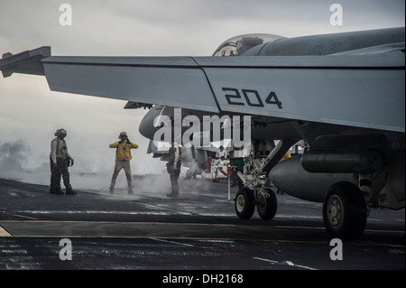 Il capo di aviazione di Boatswain Mate (manipolazione) Osvaldo Delacruz, centro, dirige un'F/A-18E Super Hornet dal Royal machete di Strike Fighter Squadron (VFA) 27 verso una catapulta sul ponte di volo della portaerei USS George Washington (CVN 73). Geo Foto Stock