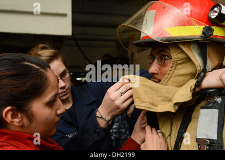 Mare Mediterraneo (ott. 22, 2013) marinai assistere Aviation Electronics Tecnico 2a classe James verde, da Owen County, Ky., come egli le attrezzature antincendio a bordo della portaerei USS Nimitz CVN (68). Nimitz è implementato il supporto di sicurezza marittima op Foto Stock