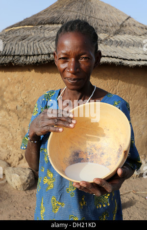 Un Fulani donna presentando calabash con latte fresco, Burkina Faso Foto Stock