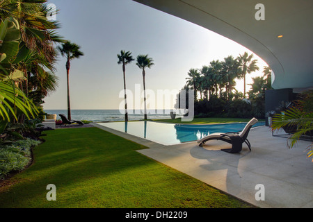 Sdraio sulla veranda accanto alla piscina di grandi e moderne villa nel sud della Spagna con vista dell'oceano in prima serata Foto Stock